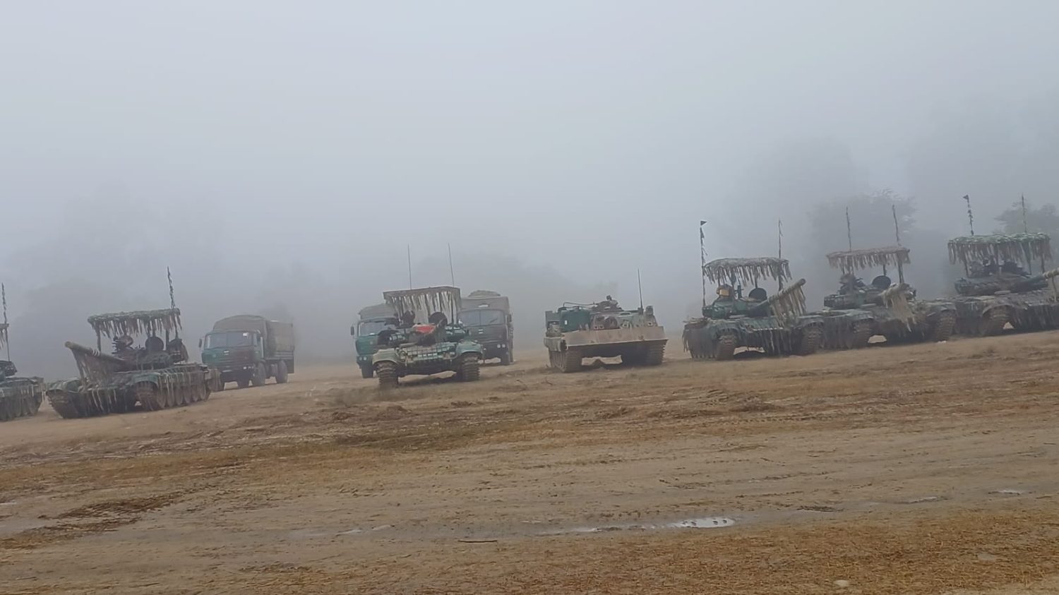Armoured column of tanks, an infantry combat vehicle and support trucks formed up in dense fog
