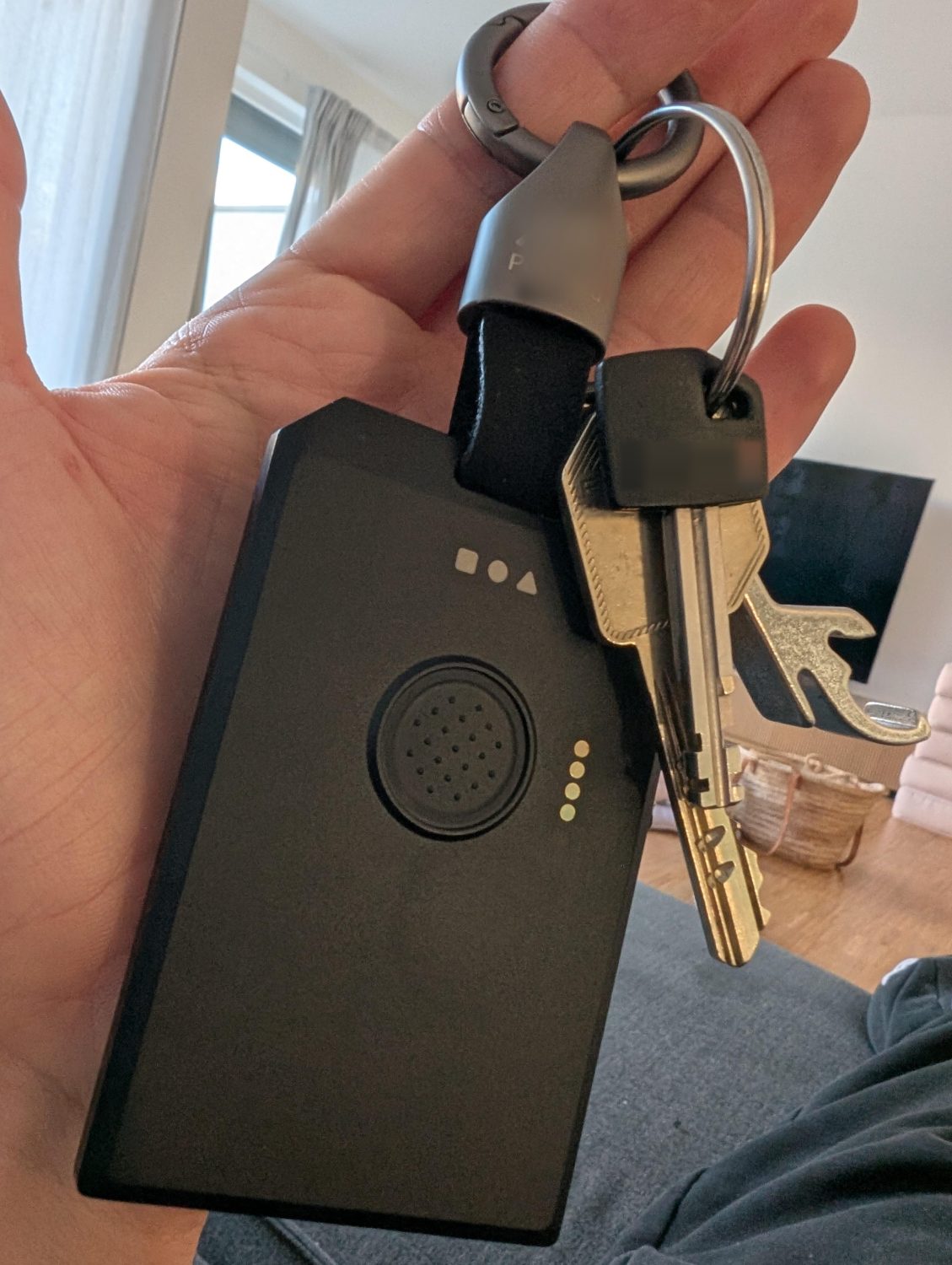 Pocket-size keychain tracker held in a hand, clipped to a keyring